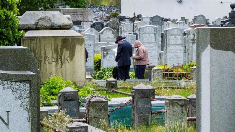 La gente lee oraciones en una tumba del Cementerio Mt Judah en Queens, Nueva York, EE.UU., 11 de mayo de 2020. EFE/EPA/JUSTIN LANE
