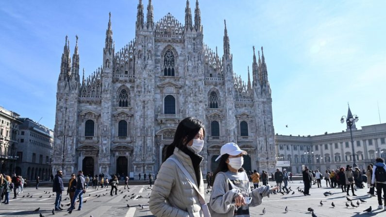 Dos mujeres con una mascarilla protectora caminan por la Piazza del Duomo, frente al Duomo, en el centro de Milán, el 24 de febrero de 2020 (Andreas Solaro/AFP vía Getty Images)