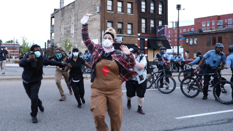 Manifestantes huyen de los agentes de policía antes de ser detenidos, durante la sexta noche de protestas y violencia tras la muerte de George Floyd, en Minneapolis, Minnesota, el 31 de mayo de 2020. (Charlotte Cuthbertson/The Epoch Times)