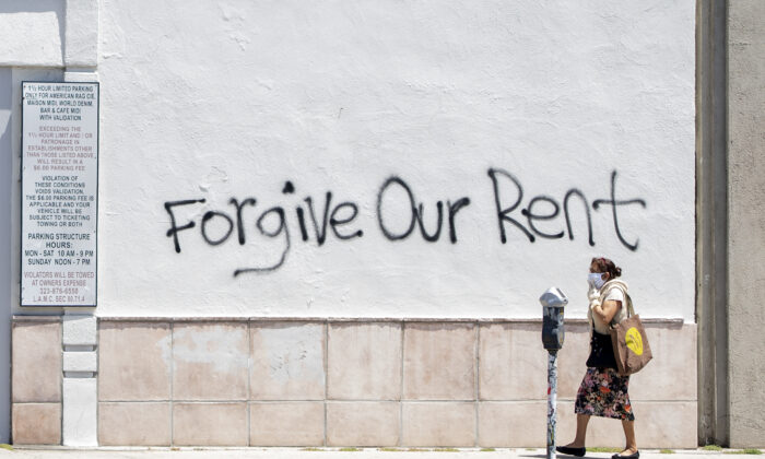 Una mujer con una mascarilla pasa por delante de un grafiti en la pared que pide perdón por el alquiler en medio de la pandemia de COVID-19, en Los Ángeles, California, el 1 de mayo de 2020. (Valerie Macon/AFP vía Getty Images)
