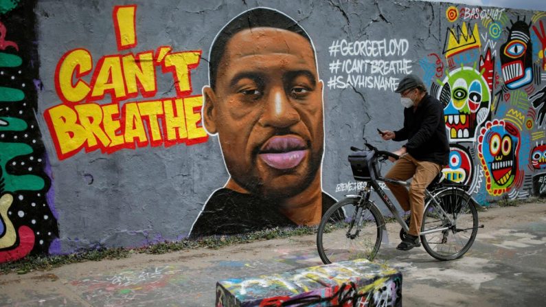 Un hombre pasa en bicicleta por delante de un mural que representa a George Floyd, que murió en Minneapolis bajo custodia policial, en Berlín, Alemania, el 30 de mayo de 2020. (David Gannon/AFP/Getty Images)
