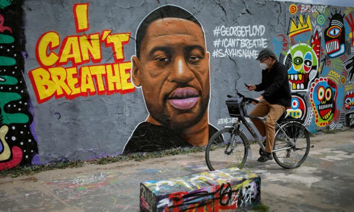 Un hombre pasa en bicicleta por delante de un mural que representa a George Floyd, quien murió en Minneapolis bajo custodia policial, en Berlín, Alemania, el 30 de mayo de 2020. (David Gannon/AFP/Getty Images)