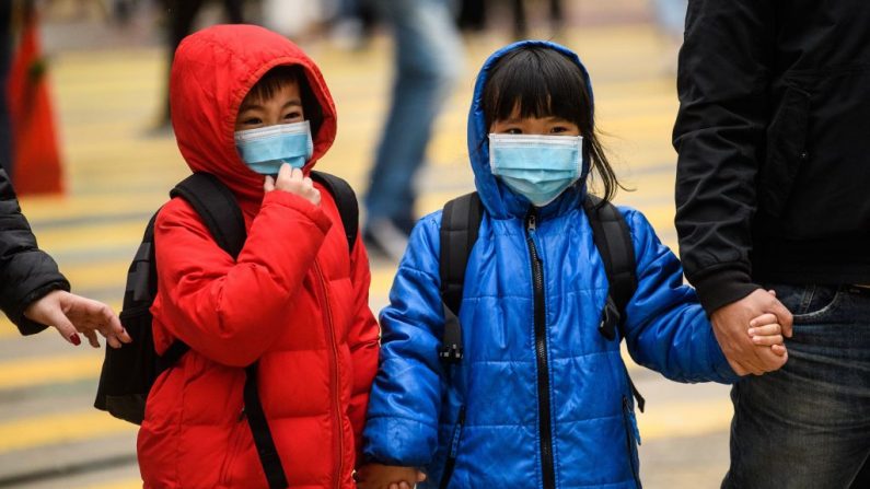 Unos niños con máscaras cruzan una carretera durante un día festivo del Año Nuevo Lunar de la Rata en Hong Kong el 27 de enero de 2020, como medida preventiva tras un brote del virus del PCCh. (Foto de ANTHONY WALLACE/AFP vía Getty Images)