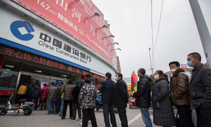 Los clientes hacen fila para tomarse las temperaturas antes de ingresar a un banco en la ciudad de Nantong, en la provincia de Jiangsu, este de China, el 25 de febrero de 2020. (STR/AFP a través de Getty Images)
