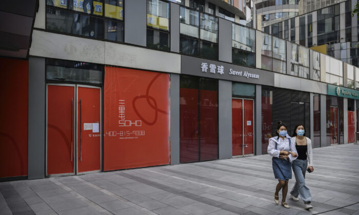 Las mujeres chinas usan máscaras protectoras mientras caminan por las tiendas que han cerrado en un distrito comercial, en Beijing, el 28 de abril de 2020. (Kevin Frayer/Getty Images)
 
