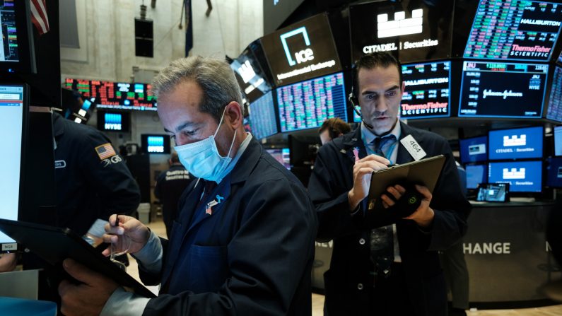 Los comerciantes, algunos con mascarillas médicas, trabajan en el piso de la Bolsa de Nueva York (NYSE) el 20 de marzo de 2020 en la ciudad de Nueva York. (Spencer Platt/Getty Images)