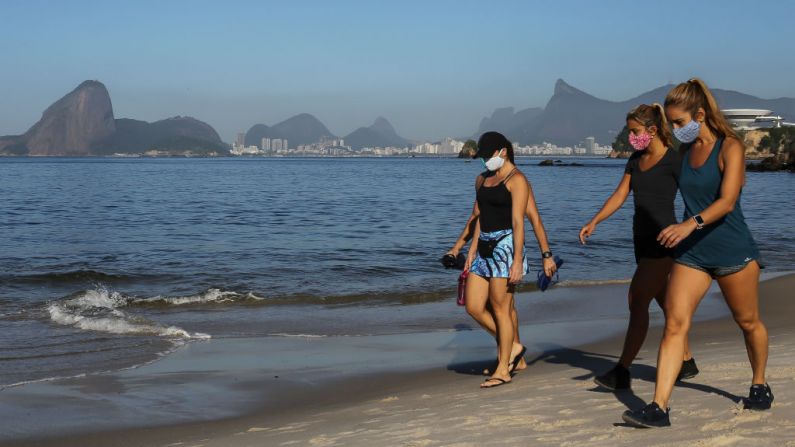 Gente caminando con cubrebocas en la playa de Icarai, con el Pan de Azúcar de fondo, durante la pandemia del virus del PCCh (COVID-19) el 21 de mayo de 2020 en Niteroi, Brasil.  (Luis Alvarenga/Getty Images)