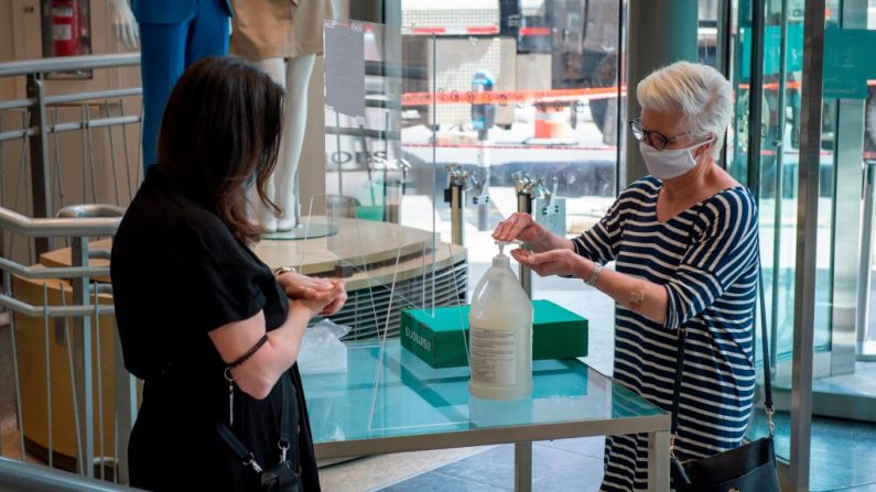 Una empleada (i) de una tienda Simons explica los procedimientos de seguridad sanitaria a una cliente en Montreal (Canadá) el 25 de mayo de 2020. (Foto de SEBASTIEN ST-JEAN/AFP vía Getty Images)