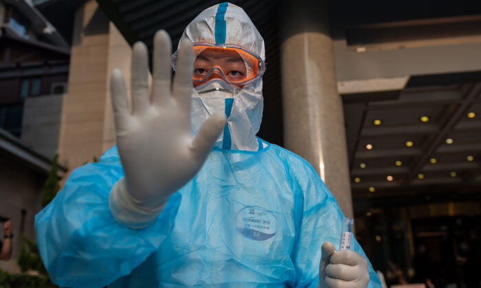 Un trabajador médico con equipo de protección completa hace gestos mientras se prepara para tomar muestras de hisopado de un periodista (no aparece en la foto) para la prueba de la COVID-19 en el hotel Diaoyutai de Beijing, China, el 28 de mayo de 2020. (NICOLAS ASFOURI/AFP vía Getty Images)