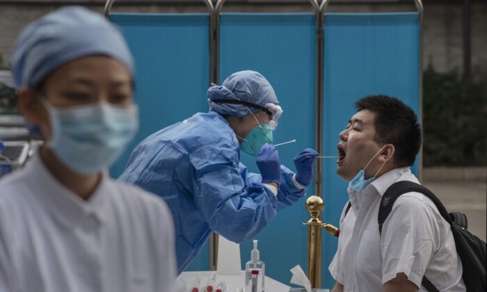 Un trabajador sanitario chino realiza una prueba de ácido nucleico a un periodista que cubre los acontecimientos en torno al Congreso Nacional del Pueblo en Beijing, China, el 28 de mayo de 2020. (Kevin Frayer/Getty Images)
