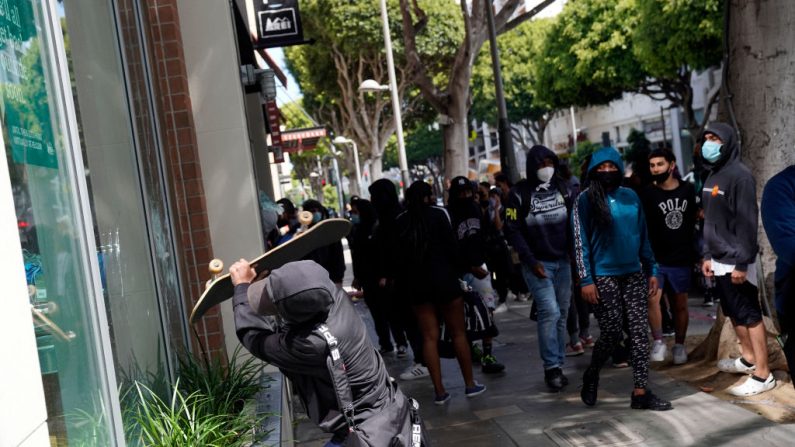 Un hombre intenta romper la ventana de una tienda con una patineta durante las protestas y disturbios generalizados en respuesta a la muerte de George Floyd el 31 de mayo de 2020 en Santa Mónica, California. (Warrick Page/Getty Images)