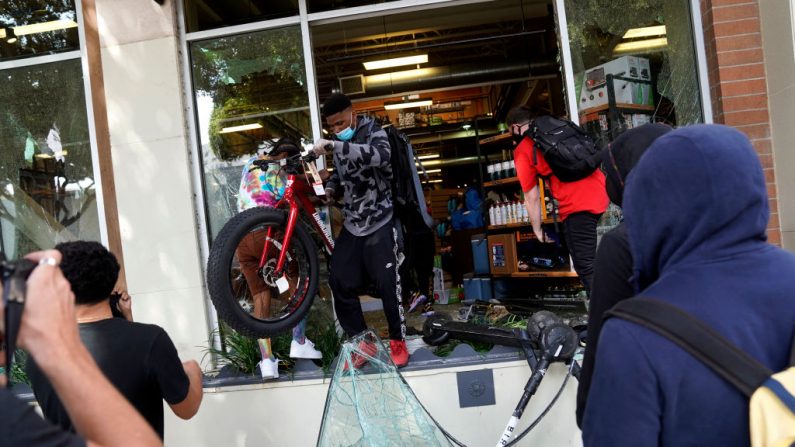 La gente se escapa con la mercancía de una tienda durante las protestas y disturbios generalizados en respuesta a la muerte de George Floyd el 31 de mayo de 2020 en Santa Mónica, California. (Warrick Page/Getty Images)