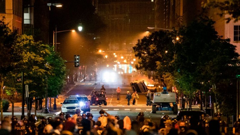 Un auto es volteado y otro se quema mientras los agitadores y la policía se enfrentan cerca de la Casa Blanca, en protesta por la muerte de George Floyd a manos de la policía de Minneapolis en Washington, D.C. el 31 de mayo de 2020. (Foto de SAMUEL CORUM/AFP a través de Getty Images)
