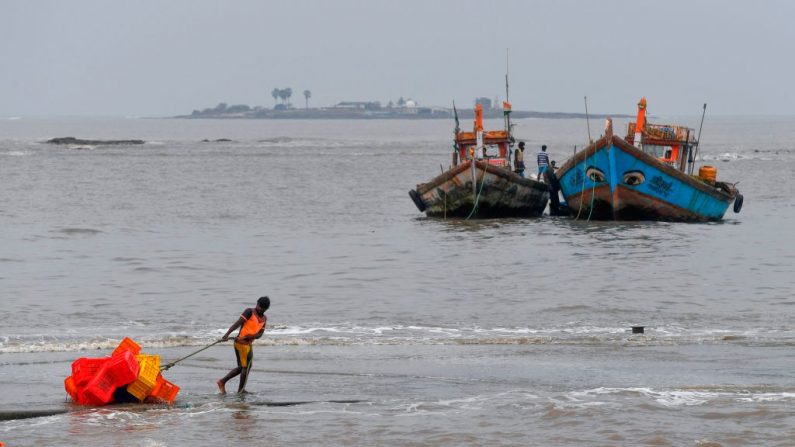 Un pescador tira de una carretilla llena de cajas hacia el interior, antes de una tormenta ciclónica que puede golpear la costa norte de Maharashtra y Gujarat (India), en el pueblo pesquero de Madh, en la costa noroeste de Mumbai, el 2 de junio de 2020. (INDRANIL MUKHERJEE/AFP vía Getty Images)