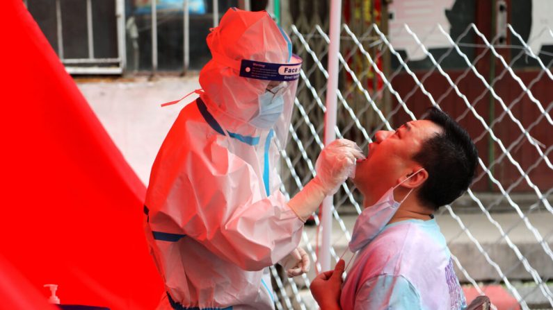 Un trabajador médico toma una muestra de hisopado de un residente para analizar el virus del PCCh en una calle de Mudanjiang, China, el 3 de junio de 2020. (STR/AFP a través de Getty Images)