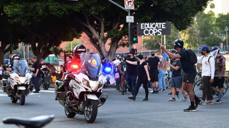 Policías en motocicleta son volteados por los agitadores mientras cruzan una intersección donde la gente se reunió para hacer disturbios por la muerte de George Floyd bajo custodia policial, en Los Ángeles, California, el 3 de junio de 2020. (Foto de Frederic J. BROWN / AFP) (Foto de FREDERIC J. BROWN/AFP a través de Getty Images)
