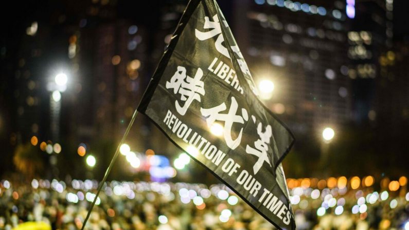 Los asistentes izan una bandera que dice "Libera a Hong Kong, la revolución de nuestro tiempo" durante un acto conmemorativo a la luz de las velas en el parque Victoria de Hong Kong el 4 de junio de 2020. (ANTHONY WALLACE/AFP vía Getty Images)