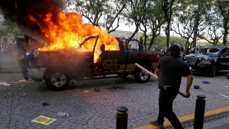 Manifestantes queman vehículos de la policía durante una protesta tras la muerte de un joven mientras estaba bajo custodia policial, después de haber sido detenido presuntamente por no cumplir las medidas para evitar la propagación del COVID-19, el 4 de junio de 2020 en Guadalajara, estado de Jalisco, México. (Foto de ULISES RUIZ/AFP vía Getty Images)