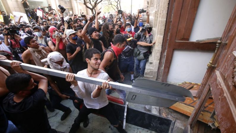 Manifestantes rompen una puerta durante una protesta tras la muerte de un joven mientras estaba bajo custodia policial, después de haber sido detenido supuestamente por no cumplir con las medidas para prevenir la propagación del COVID-19, el 4 de junio de 2020 en Guadalajara, estado de Jalisco, México. (ULISES RUIZ/AFP vía Getty Images)