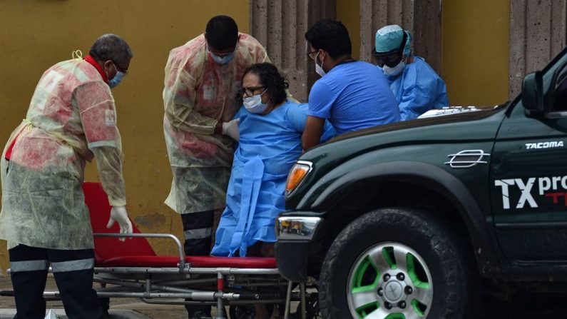Miembros de la Cruz Roja Hondureña ayudan a una anciana que permaneció en el Hospital General de San Felipe -utilizado para pacientes infectados con el COVID-19- a subir a una camilla para ser trasladada en una ambulancia en Tegucigalpa, el 5 de junio de 2020. (Foto de ORLANDO SIERRA/AFP vía Getty Images)