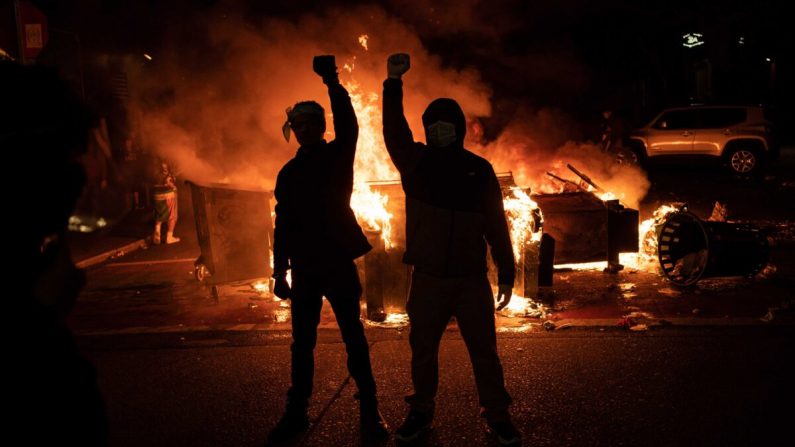 Los manifestantes levantan sus puños mientras el fuego arde en la calle después de los enfrentamientos con fuerzas policiales cerca de la comisaría del este de Seattle, en Seattle, Washington, el 8 de junio de 2020. (David Ryder/Getty Images)