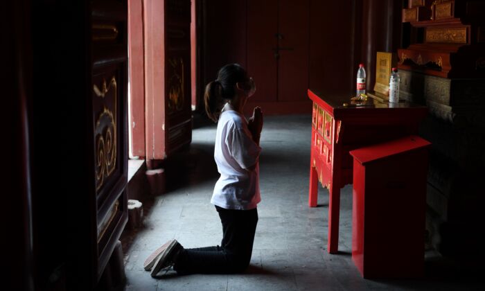 Una mujer con mascarilla ora en el Templo Lama en Beijing, China, después de que reabrió el 10 de junio de 2020. (GREG BAKER / AFP a través de Getty Images)