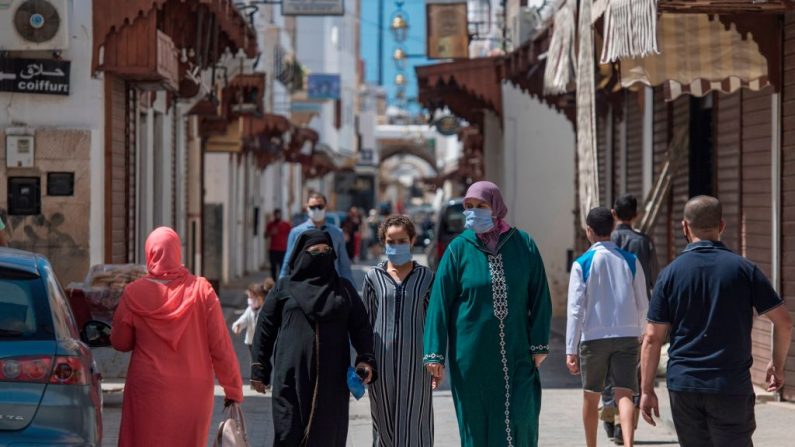 Los peatones, con máscaras protectoras debido a la pandemia de COVID-19, pasan por delante de las tiendas cerradas en la capital marroquí, Rabat, el 10 de junio de 2020. (Foto de FADEL SENNA/AFP vía Getty Images)