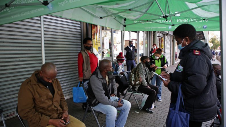 La gente espera a ser examinada durante una prueba de detección del COVID-19 en el Bloed Street Mall en el distrito comercial central de Pretoria (Sudáfrica), el 11 de junio de 2020. (Phill Magakoe/AFP vía Getty Images)