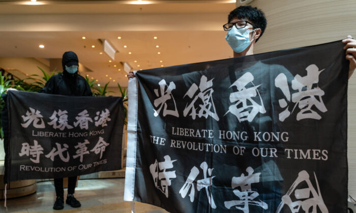 Los partidarios de la democracia sostienen pancartas y gritan consignas mientras se reúnen en un centro comercial durante una protesta a la hora del almuerzo, en Hong Kong, el 12 de junio de 2020. (Anthony Kwan/Getty Images)