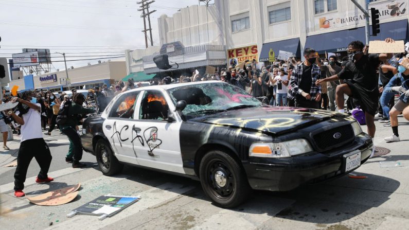Un vehículo de la policía de Los Ángeles comienza a arder después de ser incendiado por los agitadores durante los disturbios que siguieron a la muerte de George Floyd el 30 de mayo de 2020 en Los Ángeles, California. (Mario Tama/Getty Images)