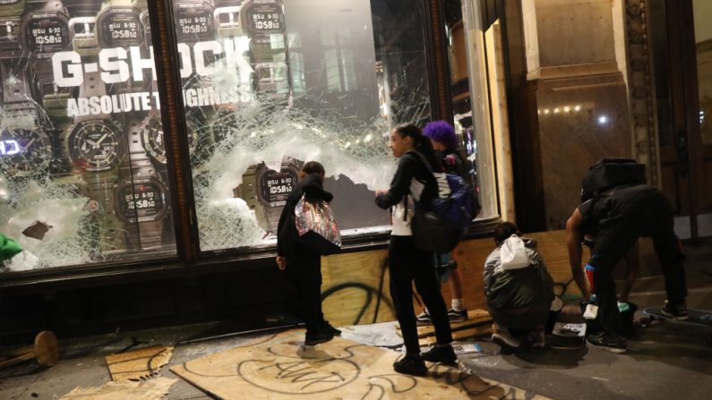 Personas se reúnen frente a una tienda saqueada en Broadway durante una noche de protestas y vandalismo por la muerte de George Floyd el 1 de junio de 2020 en la ciudad de Nueva York. (Spencer Platt/Getty Images)