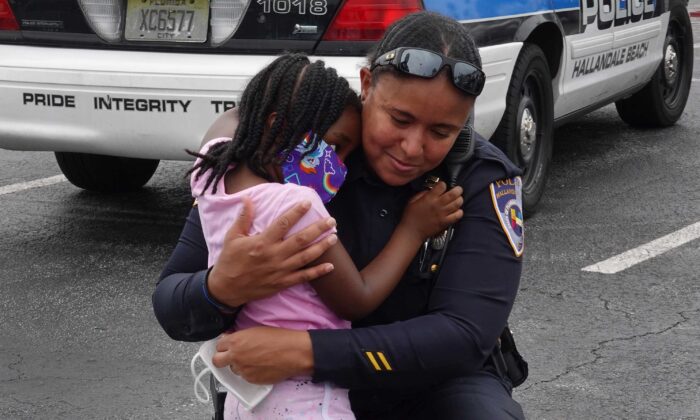 Amora Collins abraza a la capitana Megan Jones, oficial de policía de Hallandale Beach, durante una protesta contra la brutalidad policial y la reciente muerte de George Floyd, en Hallandale Beach, Florida, el 3 de junio de 2020. (Joe Raedle/Getty Images)
 
