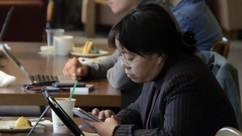 Una mujer lee su teléfono y tableta en un café en Beijing, China, el 2 de noviembre de 2012. (WANG ZHAO/AFP a través de Getty Images)