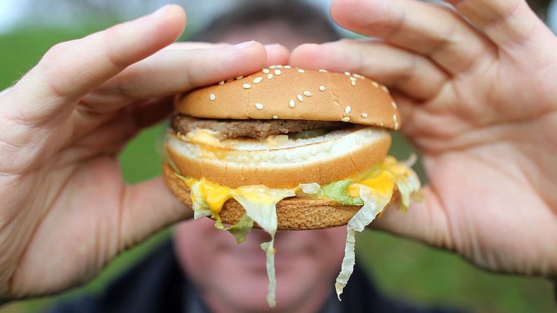 Un hombre con obesidad sostiene una hamburguesa de una tienda de comida rápida el 7 de enero de 2013 en Bristol, Inglaterra. (Matt Cardy/Getty Images)
