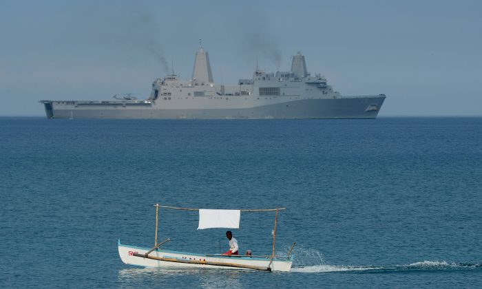 Un pescador filipino frente al buque de transporte anfibio de la Armada de los Estados Unidos USS Green Bay (LPD-20) durante un ejercicio de desembarco anfibio en una playa de San Antonio, provincia de Zambales, el 21 de abril de 2015, como parte de las maniobras anuales conjuntas de Filipinas y Estados Unidos a unas 137 millas (220 km) al este del banco de Scarborough en el Mar de China Meridional. (Ted Aljibe/AFP/Getty Images)