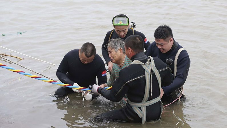 Un pasajero de edad avanzada (c) es escoltado a la orilla del río después de ser rescatado del buque Dongfangzhixing o "Estrella del Este" que se hundió en el río Yangtsé en Jianli, provincia de Hubei en China central, el 2 de junio de 2015. (STR/AFP a través de Getty Images)