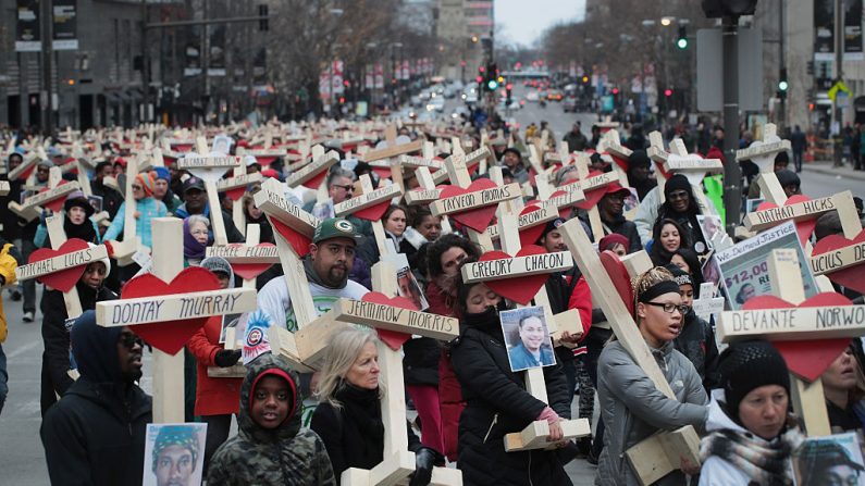 Rsidentes, activistas, amigos y familiares de las víctimas de la violencia armada marchan por Michigan Avenue llevando casi 800 cruces de madera con los nombres de los muertos por homicidio en la ciudad en 2016 en Chicago el 31 de diciembre de 2016. (Scott Olson / Getty Images)

