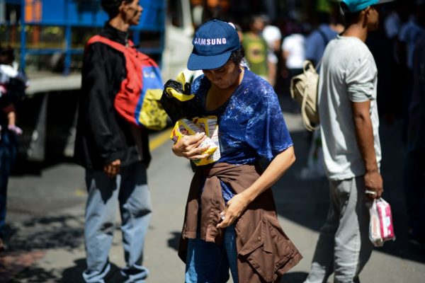 Una mujer sostiene dos bolsas de harina después de hacer cola frente a un supermercado en Caracas (Venezuela) para comprar alimentos básicos y productos domésticos el 10 de noviembre de 2017. (FEDERICO PARRA/AFP vía Getty Images)