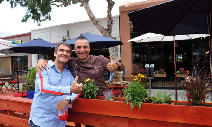 Los felices propietarios de restaurantes Laurent Vrignaud (izq) y Alessandor Pirozzi celebran la inauguración del paseo marítimo en Laguna Beach, California, el 15 de junio de 2020. (Jamie Joseph/The Epoch Times)