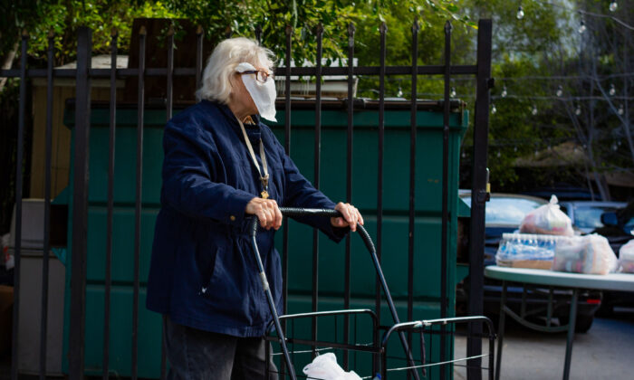 Una anciana lleva una servilleta como mascarilla mientras camina por una acera cerca de su casa en Los Ángeles, California, el 22 de junio de 2020. (John Fredricks/The Epoch Times)