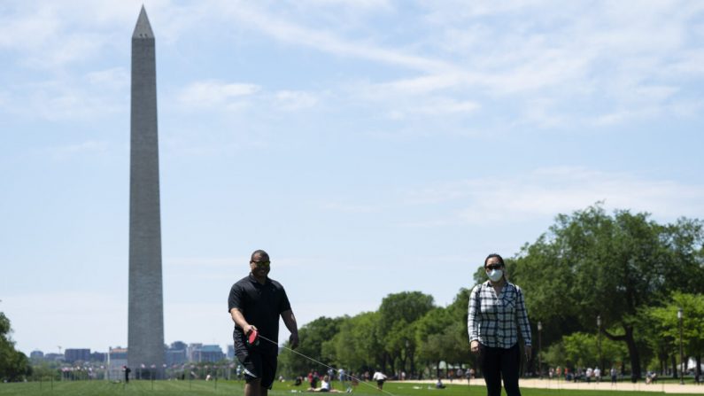 Las personas usan mascarillas protectoras mientras caminan por un corgi en el National Mall en Washington el 2 de mayo de 2020. (Sarah Silbiger/Getty Images)
