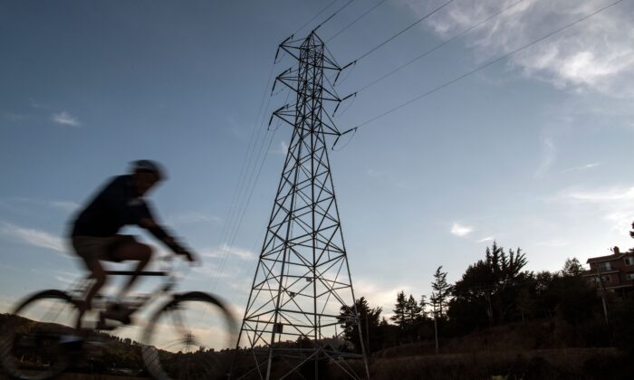 Un ciclista pasa por cables de alta tensión en Mill Valley, California, mientras un apagón estatal continúa el 10 de octubre de 2019. (Josh Edelson/AFP vía Getty Images)