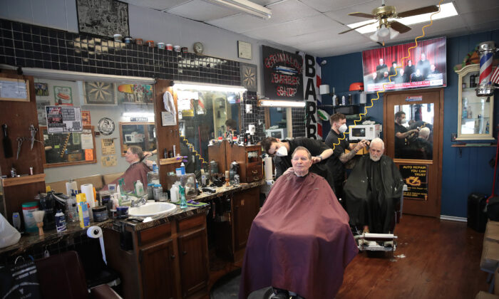 Los peluqueros Steve Grimaldi (izq.) y Chris Pouch cortan el pelo a los clientes de la peluquería Grimaldi el 13 de mayo de 2020 en Chesterton, Indiana. (Scott Olson/Getty Images)