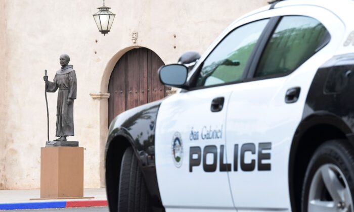 Se ve un vehículo policial estacionado cerca de una estatua del Padre Junípero Serra frente a la Misión de San Gabriel en San Gabriel, California, el 21 de junio de 2020. (FREDERIC J. BROWN/AFP vía Getty Images)