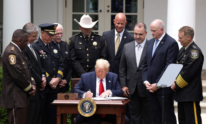 Rodeado de integrantes de organismos de seguridad, el presidente Donald Trump firma una orden ejecutiva sobre "Vigilancia policial segura para comunidades seguras" durante un evento en la Rosaleda de la Casa Blanca el 16 de junio de 2020. (Alex Wong/Getty Images)