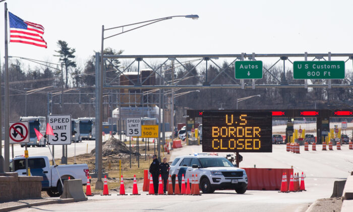 Funcionarios de aduanas de EE.UU. junto a un letrero que dice que la frontera de EE.UU. está cerrada, en la frontera de EE.UU. y Canadá, en Lansdowne, Ontario, el 22 de marzo de 2020. (Lars Hagberg/AFP/Getty Images)