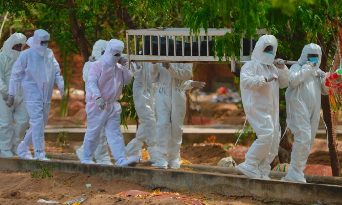 Voluntarios del Partido Socialdemócrata de la India transportan el cuerpo abandonado de una víctima que murió a causa del virus del PCCh durante un entierro en un cementerio de Chennai (India) el 16 de junio de 2020. (Arun Sankar/AFP vía Getty Images)