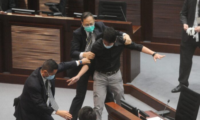 Hui Chi-fung, un legislador del Partido Demócrata, es retenido por guardias de seguridad en el Consejo Legislativo de Hong Kong (LegCo) justo antes de la votación del controvertido proyecto de ley sobre el himno nacional el 4 de junio de 2020. (Song Bilung/The Epoch Times)