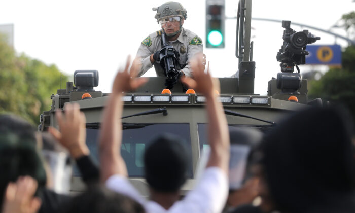 Un agente de policía apunta un arma no letal mientras varios manifestantes levantan la mano durante las manifestaciones tras la muerte de George Floyd en Santa Mónica, California, el 31 de mayo de 2020. (Mario Tama/Getty Images)