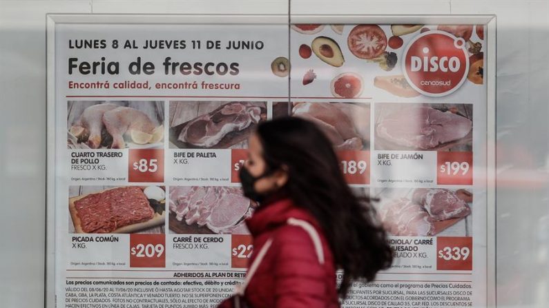 Una mujer con tapabocas camina el 11 de junio de 2020 junto a un cartel de ofertas de un supermercado, en Buenos Aires (Argentina). EFE/Juan Ignacio Roncoroni